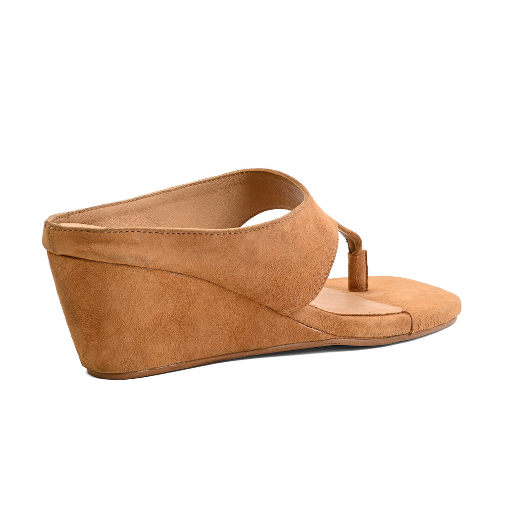 A tan suede wedge mule sandal with a toe loop, shown from a side profile view on a solid white background.